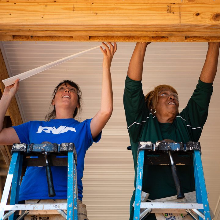 Two women install ceiling trim