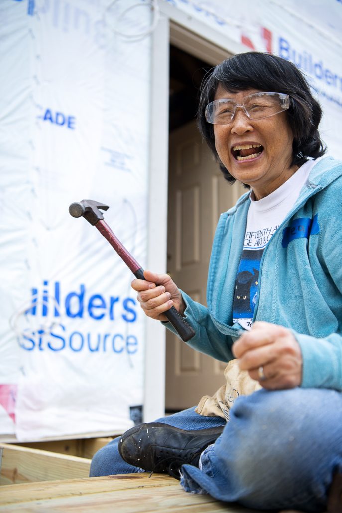 A volunteer laughs while swinging a hammer