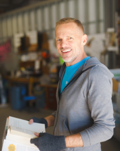 Bryan, smiling, holds a book in the Asheville ReStore's donation lane.