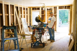 Larry stands in his living room as it's under construction.