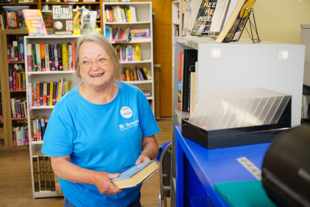 Sheila Ray stocks books on the selves outside of the Weaverville ReStore's bookstore.