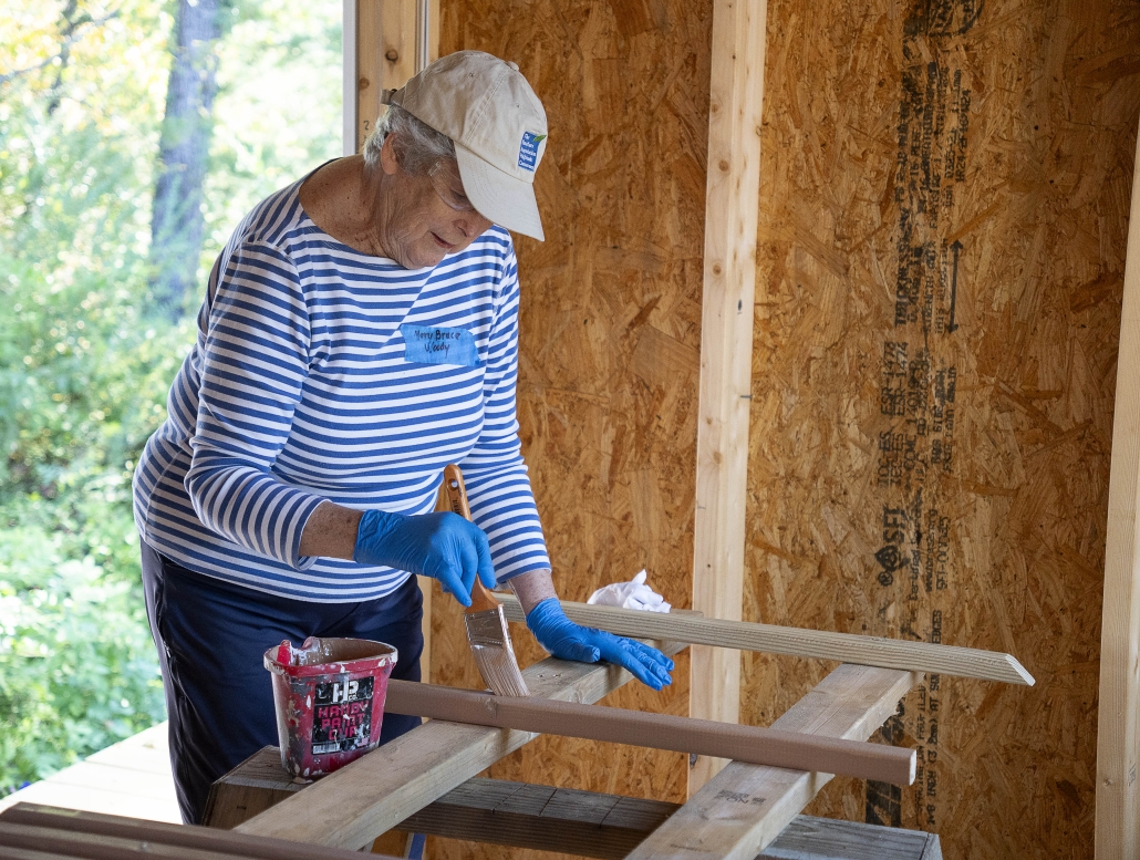 Volunteer Mary Bruce paints balusters on the construction site.
